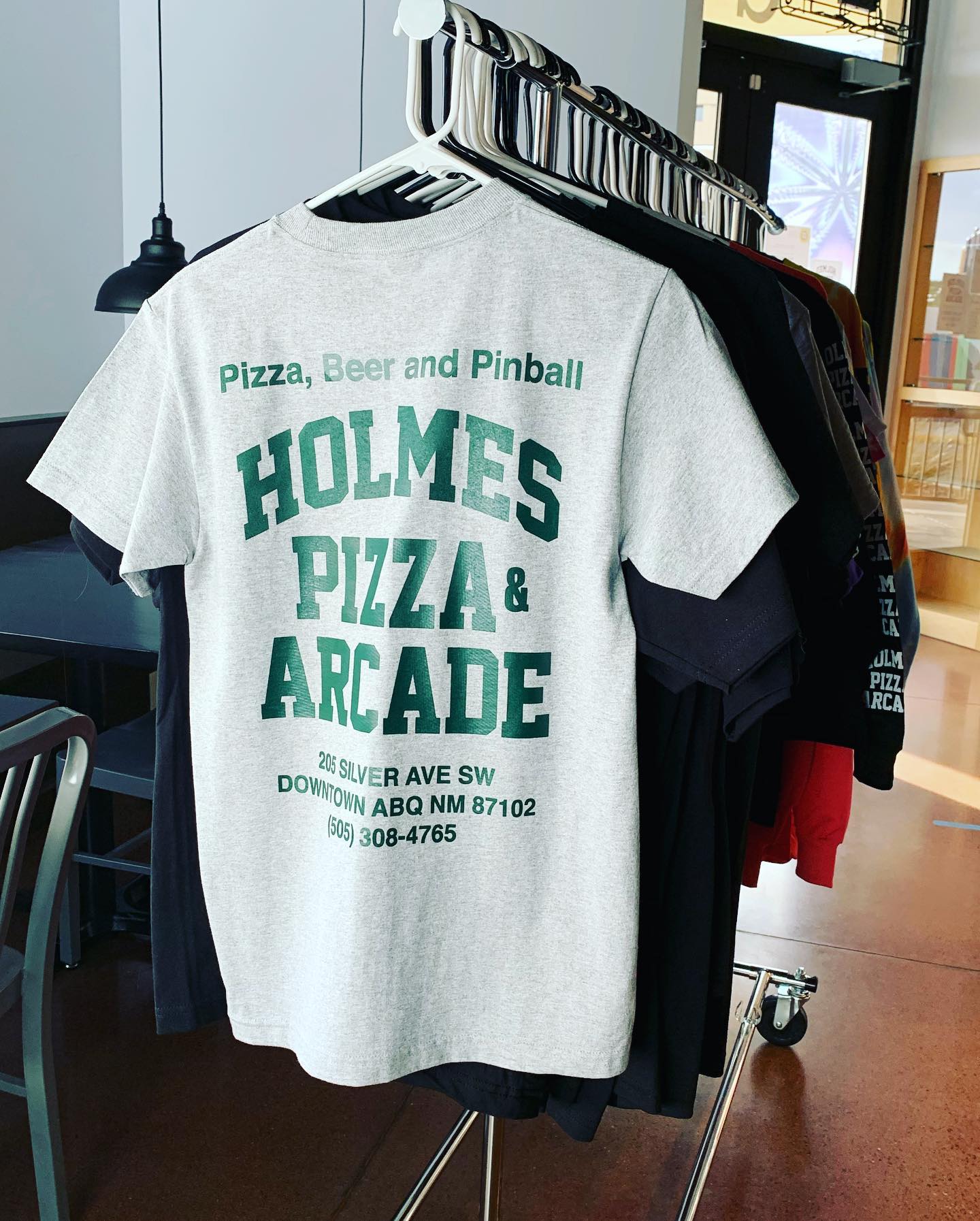 T-shirt on rack saying Pizza, Beer and Pinball, Holmes Pizza and Arcade